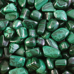 Close up of Malachite tumble stone - bands of dark and light green.
