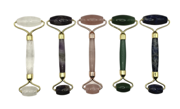 Selection of five Massage Rollers in a line - clear, pink, green and blue with gold hardware - on a white background