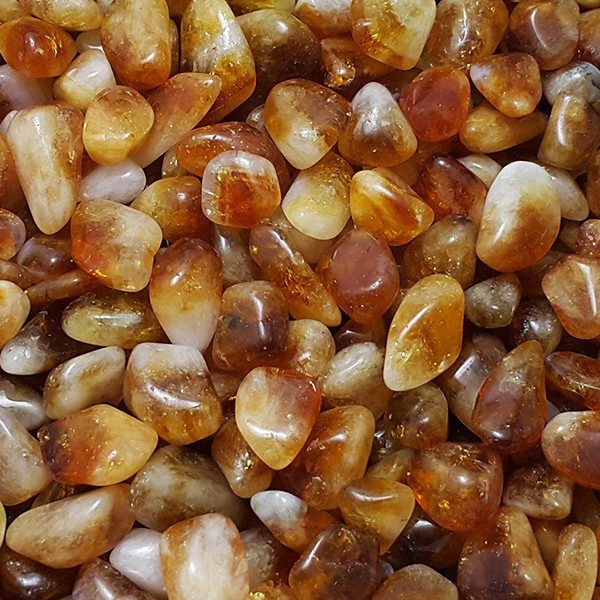 Close up of Citrine Quartz Madeira tumbledstone - half white, half dark orange stones with varying opacities.