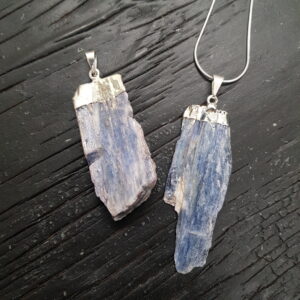 Two Blue Kyanite Blade Pendants - blue shards with silver top and bail - on a dark wooden board