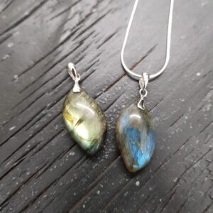 Two Labradorite AAA Drop pendants - teardrop shaped grey/green with blue flash stone with silver frame and chain - on a dark wooden board
