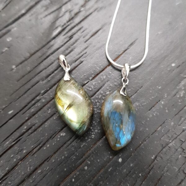 Two Labradorite AAA Drop pendants - teardrop shaped grey/green with blue flash stone with silver frame and chain - on a dark wooden board