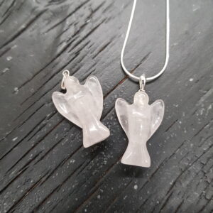 Two Rose quartz angel pendants - pale pink stone with silver tops and chain - on a dark wooden board
