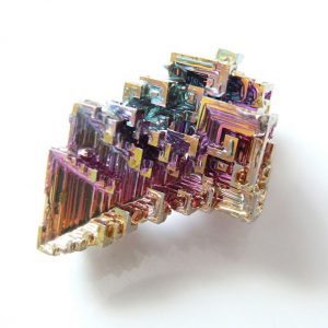 One piece of Bismuth - geometric shape with pink, blue and orange metallic colours - on a white background