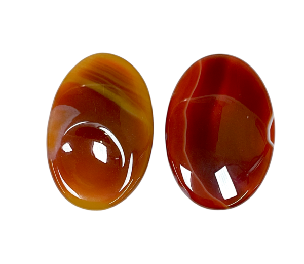 Two Carnelian Thumb Stones - red with orange and cream banding - on a white background