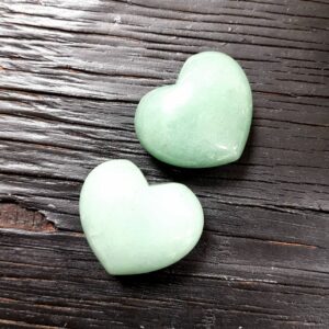 Two Aventurine hearts, green opaque, on a black wooden board