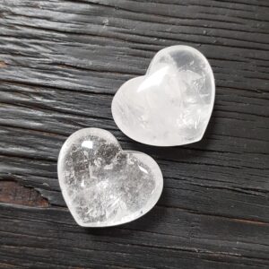 Two Crystal Hearts, clear with some clouds, on a dark wooden board