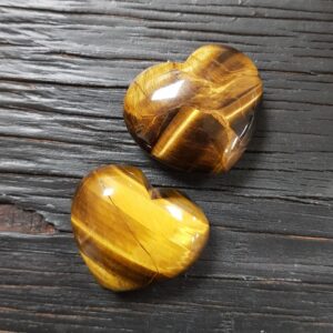 Two Golden Tigers Eye Hearts, gold and black banding, on a black wooden board