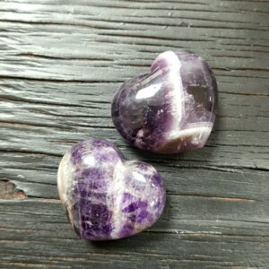 Two Banded Amethyst Hearts, purple with white banding, on a black wooden board