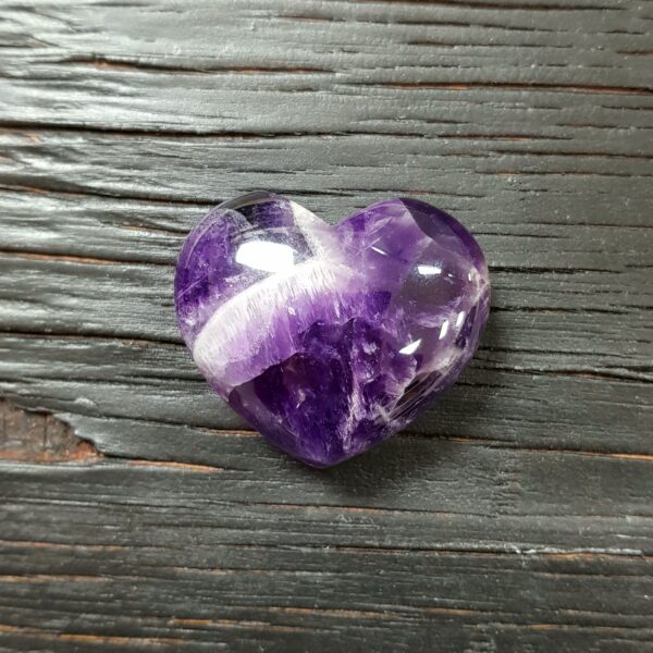 Banded Amethyst Heart, purple with white banding, on a black wooden board