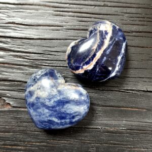 Two Sodalite Hearts - blue with white and yellow banding, on a black wooden board