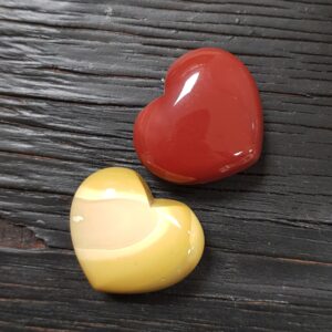 Two Mookaite hearts, one red and one yellow, on a wooden black board