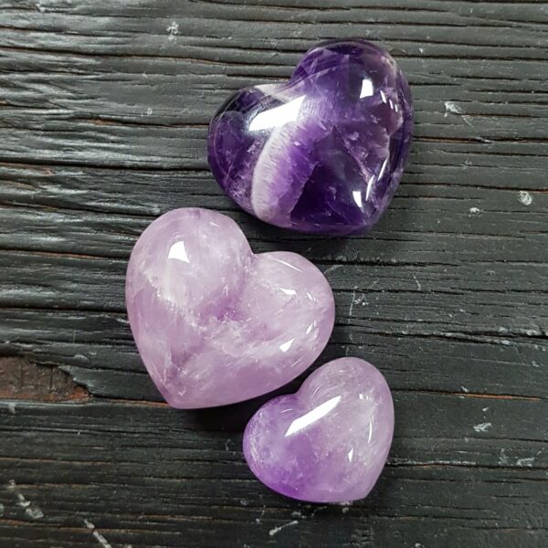 Amethyst Heart A Grade, translucent dark purple in 3 descending sizes, on a black wooden board