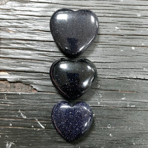 Blue Goldstone Hearts - dark blue with gold flecks, in 3 descending sizes, on a black wooden board
