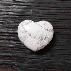 Howlite heart, white with grey marbling, on a black wooden board