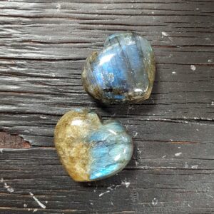 Two Labradorite Hearts, green with a brilliant blue flash, on a black wooden board
