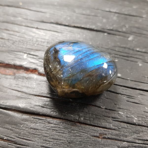Close up of Labradorite Heart, green with a brilliant blue flash, on a black wooden board