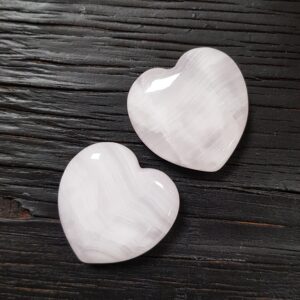 Pink Calcite hearts on a dark wooden board