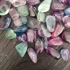 Selection of Fluorite Rainbow (A/A+ Grade), translucent green, pink, purple, blue on a black wooden board
