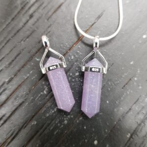Two Lepidolite A Grade Double Terminated points (pale purple facets points at both ends), on a silver chain, on a dark wooden board