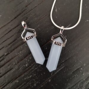 Two Angelite A+ Grade Double Terminated points (pale blue with points at both ends), on a silver chain, on a dark wooden board