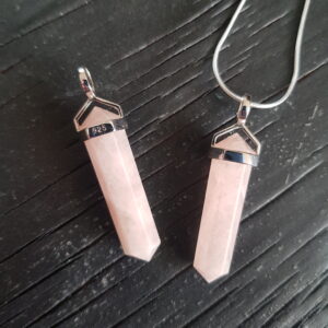Two Morganite Double Terminated points (pink facets with points at both ends), on a silver chain, on a dark wooden board