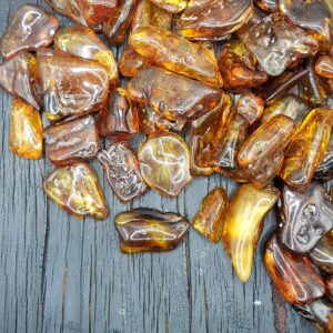 Close up of Baltic Amber - dark orange and amber coloured stones on a black wooden board