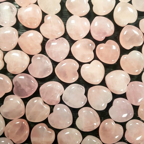 Selection of small rose quartz hearts, pink, on a black background