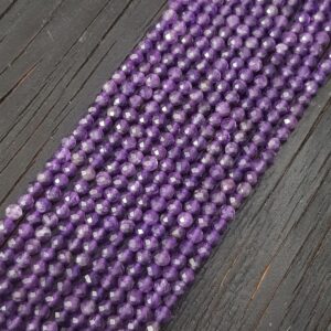 Close up of Amethyst Faceted 4mm beads - rows of small angular purple beads on a dark wooden board