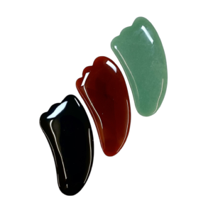 Three Gua Sha massage tools - green Aventurine, red Carnelian, Black Obsidian - on a white background
