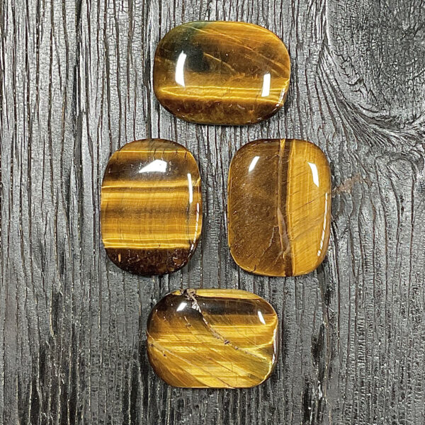 Four Tiger Eye Rectangle Stones, gold and brown banding, on a black wooden board