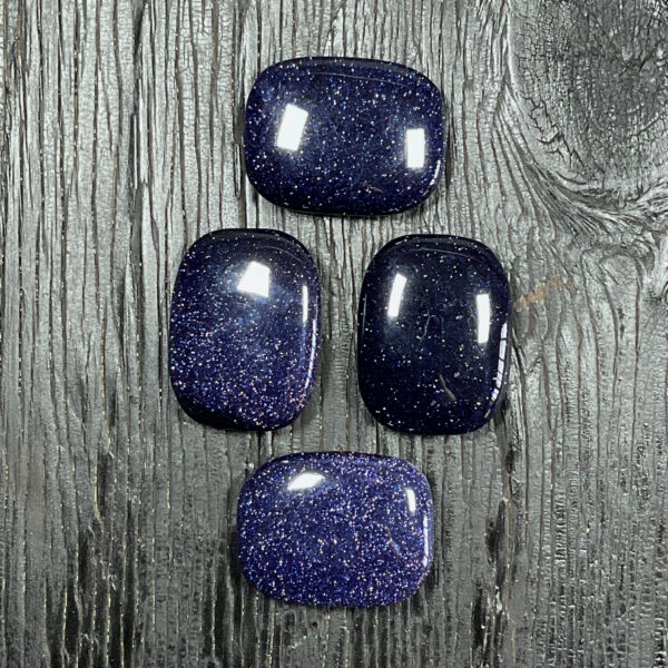 Four Blue Goldstone Rectangle Stones, blue with gold sparkling fleck, on a black wooden board