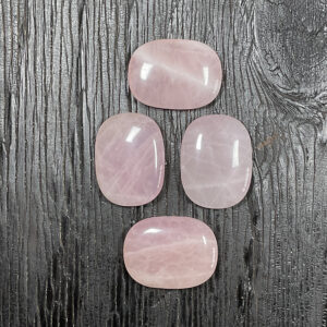 Four Rose Quartz Rectangle Stones, pale to deep pink, on a black wooden board