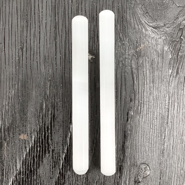 Two Selenite Wands, white sticks, on a black wooden board