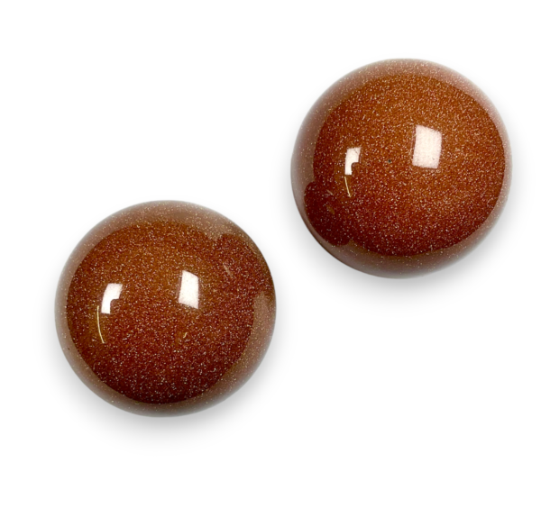 Two Goldstone spheres - brown stone with copper flecks - on a white background