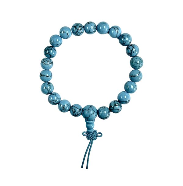 One Turquoise power bracelet viewed from the top - blue with black veining round beads with one larger bead - on a white background