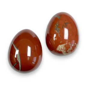 Two Red Jasper eggs - red stone with yellow banding - on a white background