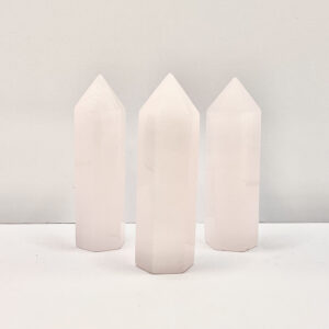 Four polished points in an ascending line - pale pink calcite - on a white background