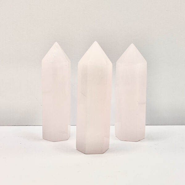 Four polished points in an ascending line - pale pink calcite - on a white background