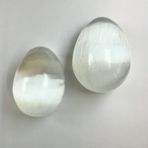 Two Selenite eggs - pearlescent white stone - on a white background