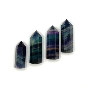 Four polished points in a descending line -green and purple banded fluorite - on a white background