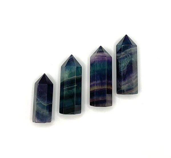 Four polished points in a descending line -green and purple banded fluorite - on a white background