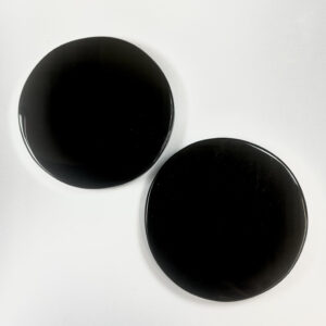 Two black obsidian mirrors - circular and flat black - on a white background