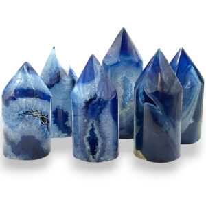 Group of polished agate points - blue and grey, with banding and patches of sparkling druze - on a white background
