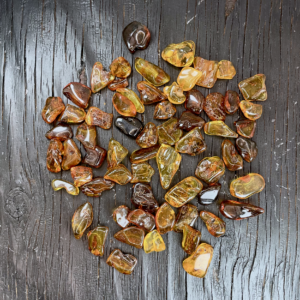 Close up of Baltic Amber - dark orange and amber coloured stones on a black wooden board