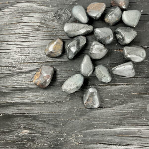 Example of Bornite tumble stone - matte metallic grey stone - on a black background