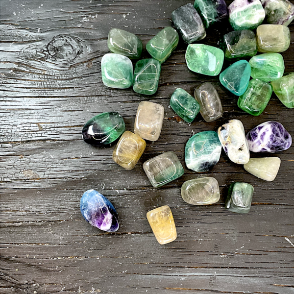 Example of Fluorite tumble stone - translucent stones of purple, green, blue, white, yellow, and clear - on a black background