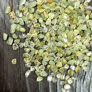Example of Green Beryl - small chips of transparent green tumble stone - on a dark wooden board