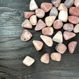 Example of Petalite (Pink - A Grade) tumble stone - pink/red spots in a grey stone - on a black background