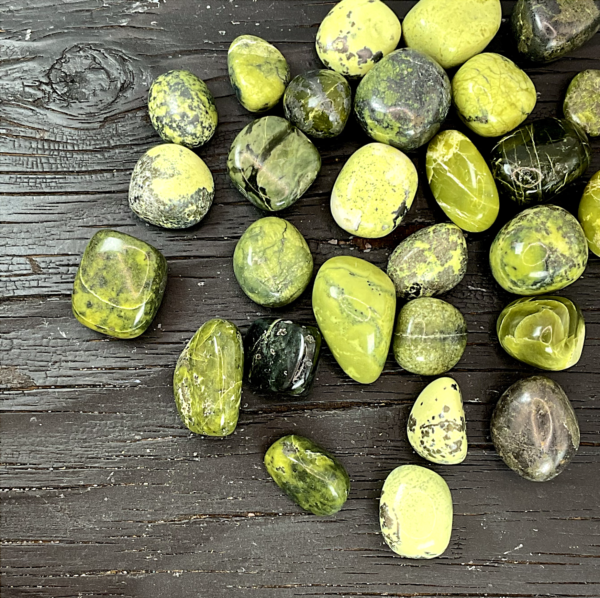 Example of Serpentine tumble stone - lime green stone with patches of black and yellow - on a black background